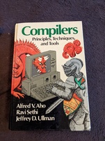 Compilers - Principles, Techniquest, and Tools. Features a knight fully clad in armor that is labeled 'Data Flow Analysis' using a computer where a dragon labeled 'Complexity of Compiler Design' has stuck its head through the back of the monitor and is glaring at the knight through the glass