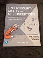 Cybersecurity Myths and Misconceptions book cover. Features a cartoon fox wearing a hat and a backpack shining a flashlight on a wall where some circuitry and some images representing some cybersecurity concepts: a tower, an eyeball similar to the on on insecure.org, a trojan horse, a heart with an arrow through it (perhaps to represent Heartbleed), and the word 'L33T'