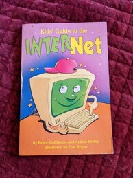 Kids' Guide to the Internet book cover. Features a computer with a human face wearing a backwards baseball cap on its monitor. It is looking at the user and using its hands to press one of the buttons on its keyboard. 