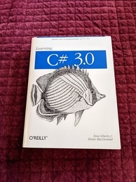 Learning C# book cover from O'Reilly. Features a wandering chaetodon swimming beneath the logo