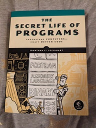 Cover of the Secret Life of Programs book. Features a robot investigating some ruins. It peeks out from behind a wall where the bricks are labeled: C++, Fortran, Assembly Language, Binary. Other bricks are labeled with heiroglyphs and various pieces of computer hardware rendered in line art.