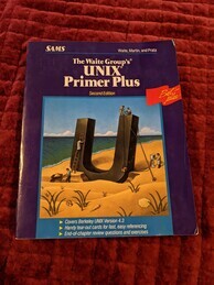 Cover of the UNIX Primer Plus. Features an image of workers excavating a large 'U' from a sand-like substance. One worker hauls away a wheelbarrow of material, one worker ascends a ladder to inspect a crack. Two workers on top of the 'U' work on either raising or lowering a block-shaped object. One worker stands at a computer attached to the 'U' with electrodes and appears to be typing. The blue water-like area in the background appears to have circuitry embedded in it.