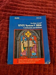 Cover of the UNIX System V Bible. Features a drawing of a stained glass window depicting two figures, nroff and chmod, as they present a book to the viewer