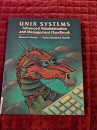 Cover of the UNIX Systems Advanced Administration and Management Handbook. Features a green background with reddish formations that could be hills or clouds. In the foreground is a dragon preparing to type on a keyboard