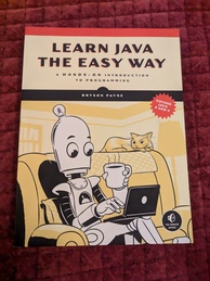 Learn Java the Easy Way book cover. Features a robot sitting on a loveseat, working on a laptop and holding a cup containing a hot substance. A cat looks on from the comfort of the antemacassar