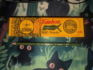 Tombow 8900 Pencil with its box. The box is a fancy yellow with a realistic dragonfly drawn on it